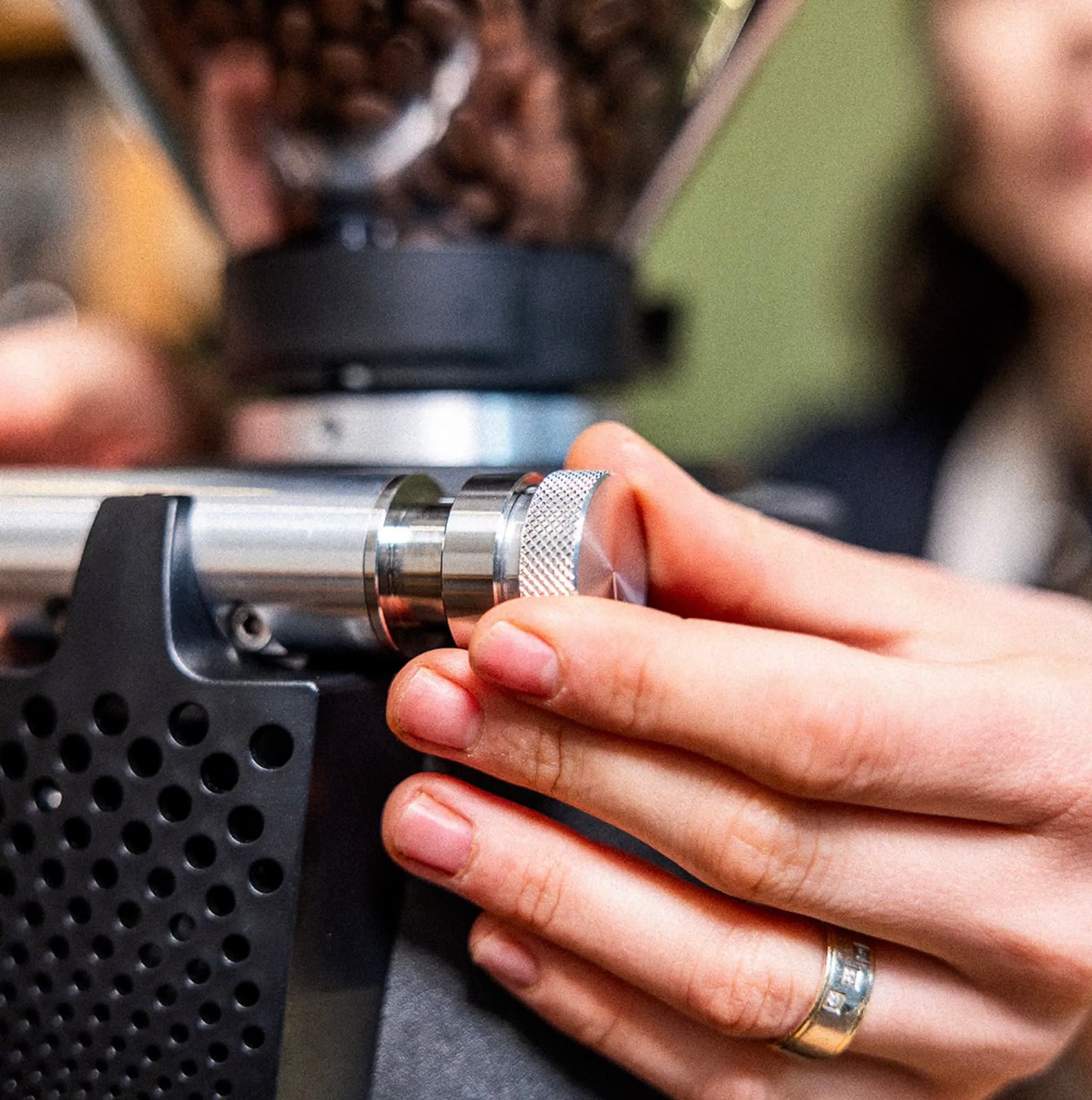 Person adjusting a coffee grinder with a blurred background